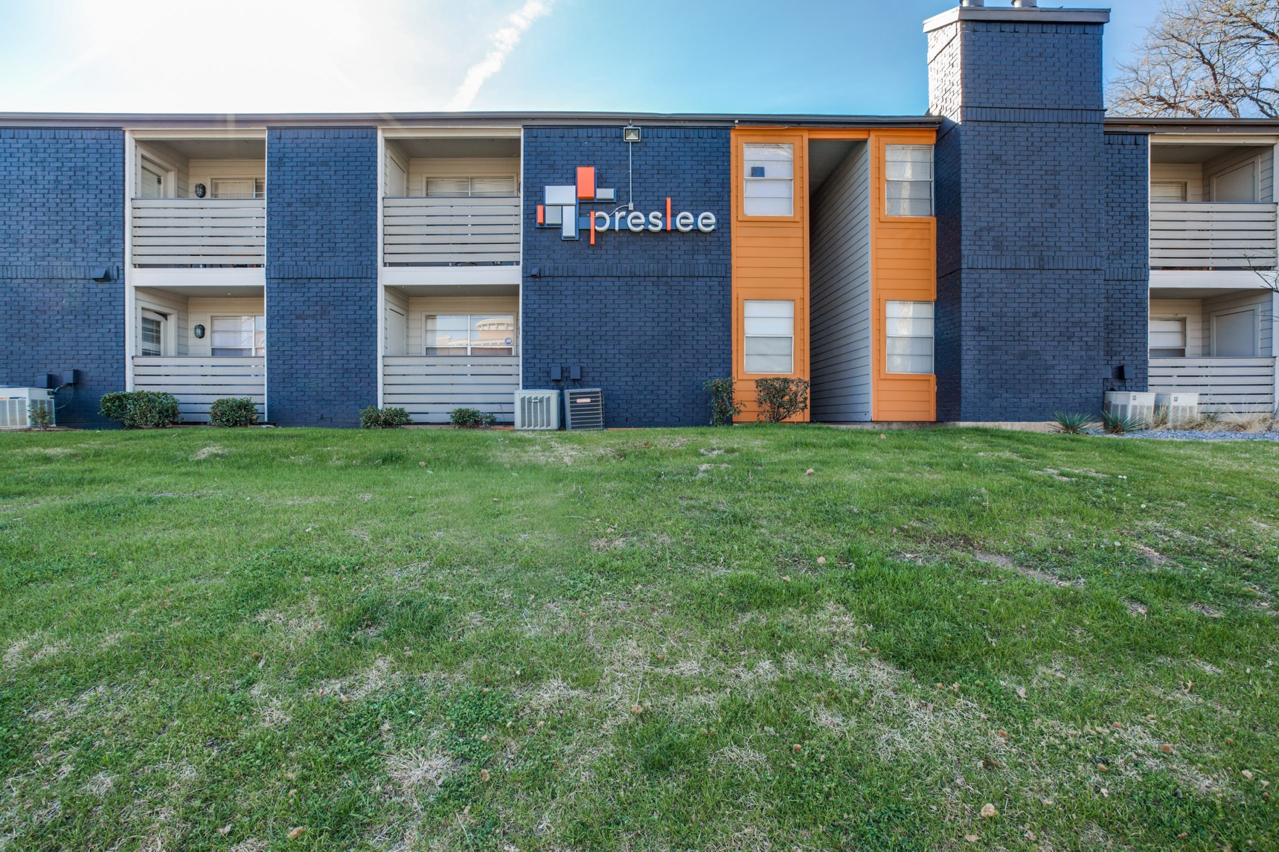 the exterior of an apartment building with blue and orange accents at The Preslee