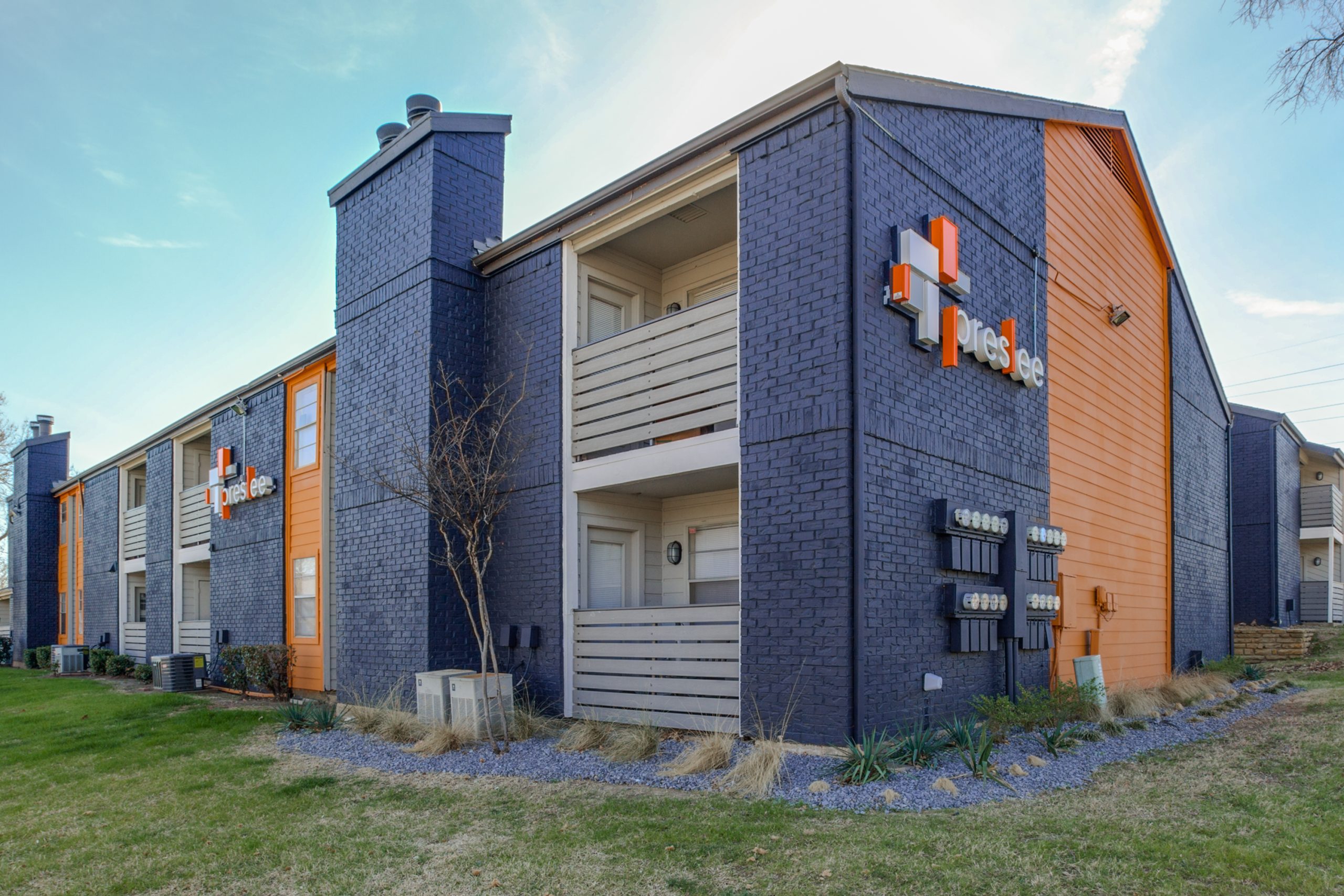 the exterior of an apartment building with orange and blue trim at The Preslee