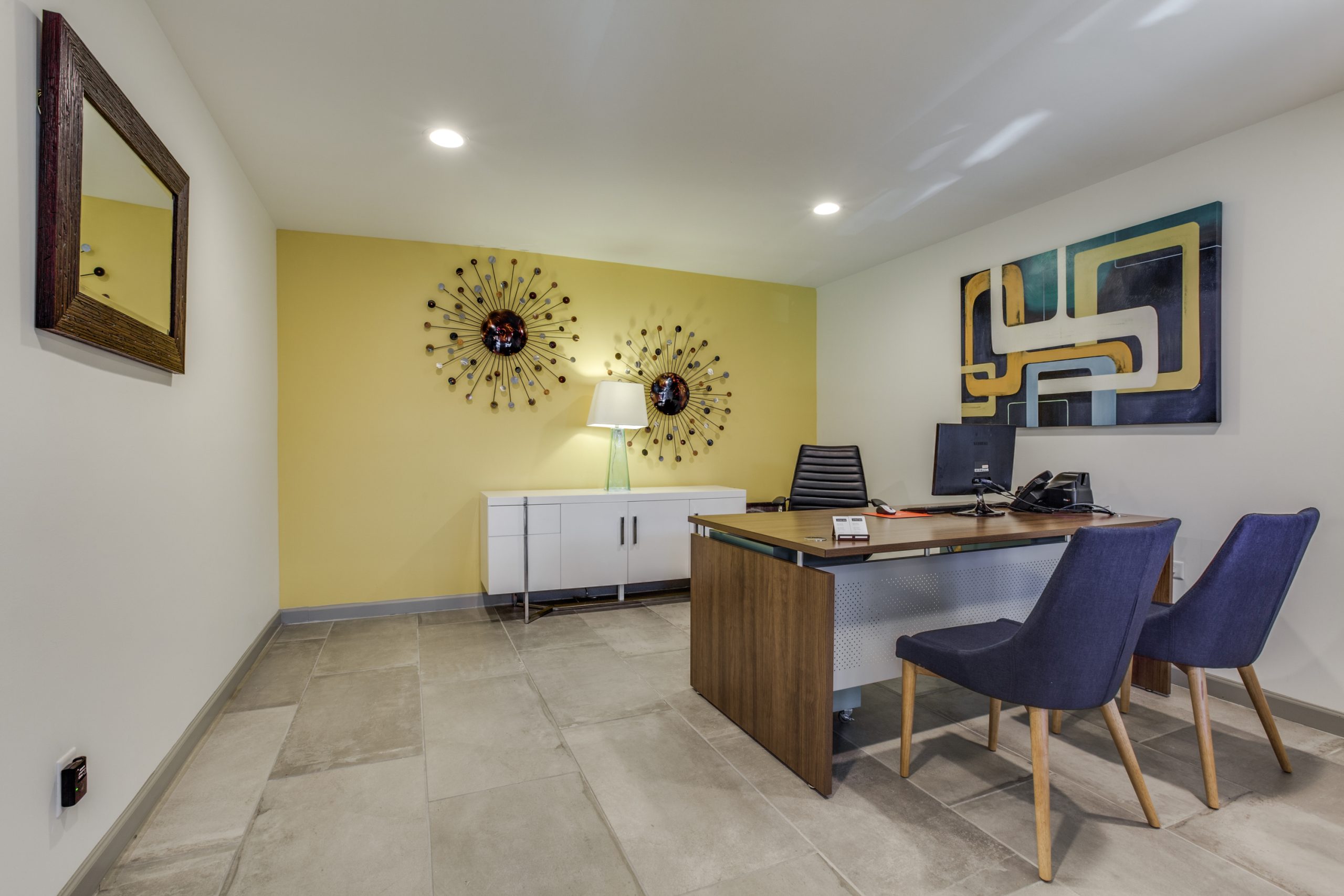 a modern office with yellow walls and blue chairs at The Preslee